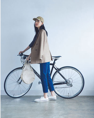 ジャケットにデニムを合わせて自転車を押す女性
