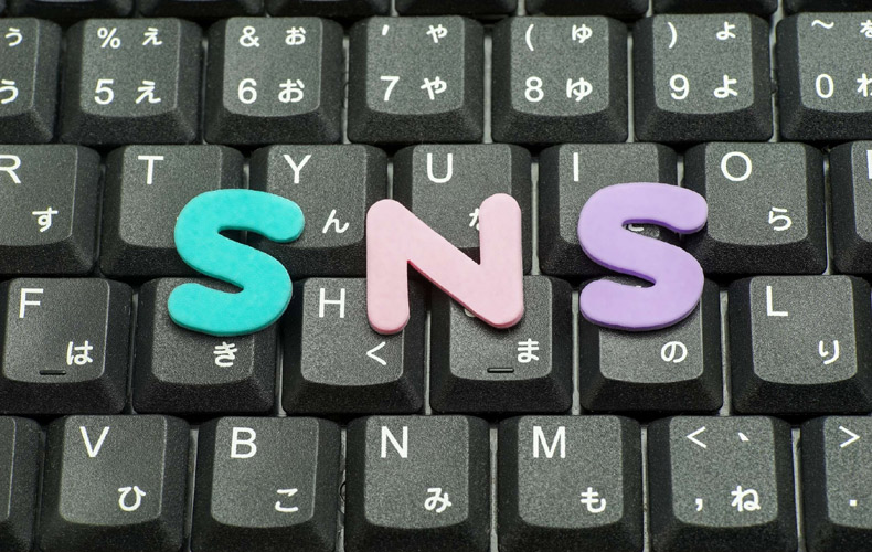 PCのキーボードの上に「SNS」の文字が乗っている写真