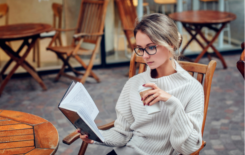 カフェでコーヒーを片手に本を読む女性