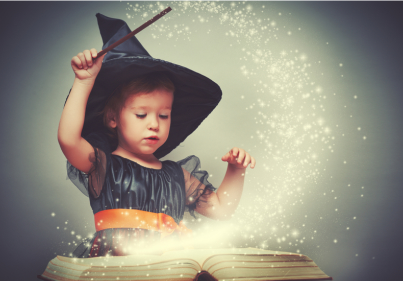 魔女の仮装で本に魔法をかける子供