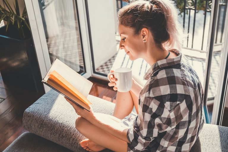 窓辺でリラックスして読書する女性