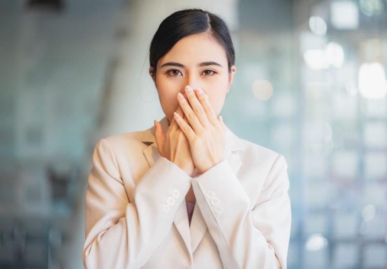 両手を口にあてる女性