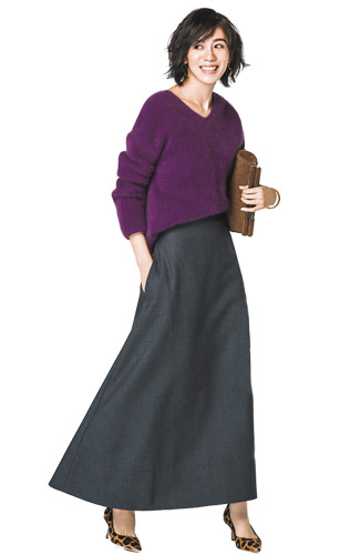 濃い紫のニットに暗いグレーのマキシ丈フレアスカートをあわせたモデル写真