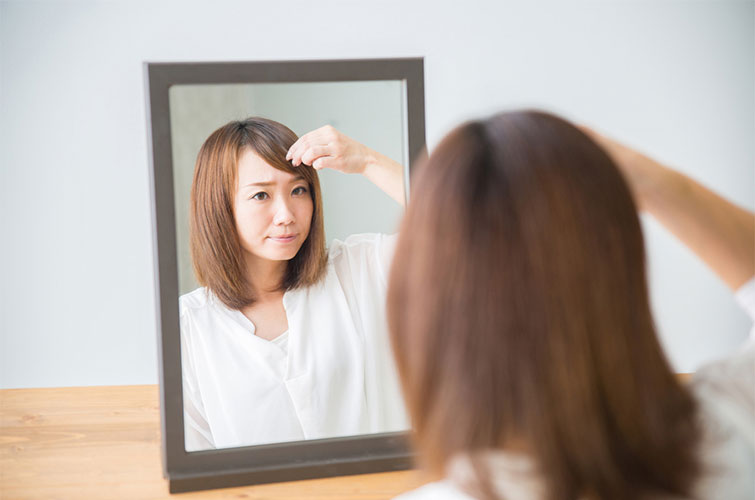 鏡に映った前髪を気にする女性