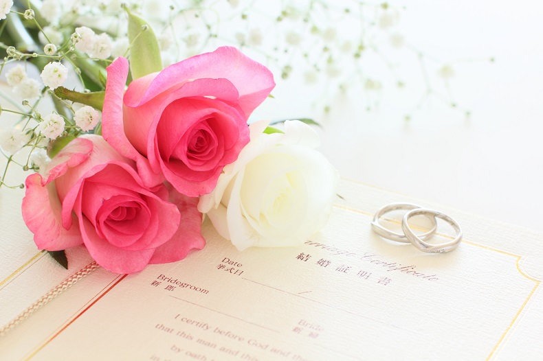 結婚証明書と薔薇の花、重なったふたつの指輪