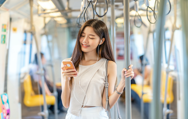 電車内でイヤホンで音楽を聴く女性 