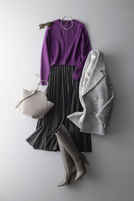 濃い紫のカーディガンと暗いグレーのロングプリーツスカートにライトグレーのミドル丈コートをあわせたコーデ写真