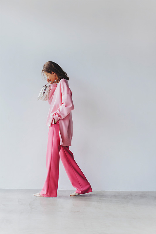 薄めのピンク色のカーディガンと濃いピンク色のパンツを着用したモデル写真