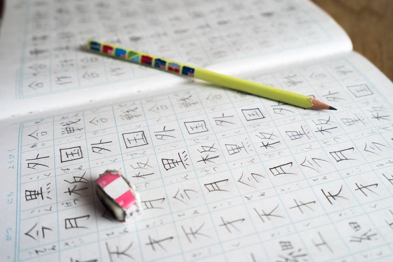 小学生が書いた漢字練習帳。ノートの上に鉛筆と使いかけの小さな消しゴムがのっている。