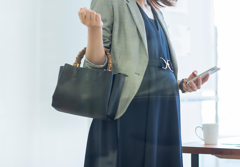 鞄とスマホ持つ妊婦 ビジネスウーマン