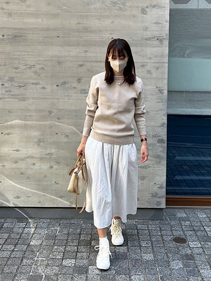 ベージュニットと白スカートを着ているドマーニスト 吉田美帆さんの写真