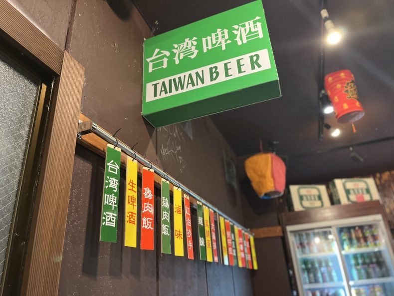 台湾ビールやメニューの板が掛けられた店内の壁の画像