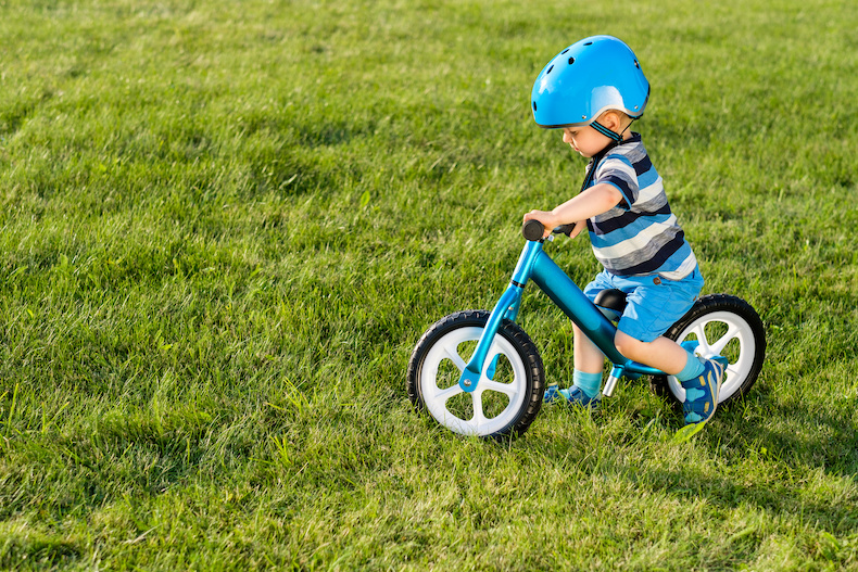 青いヘルメットを着けて青い自転車に乗る子ども