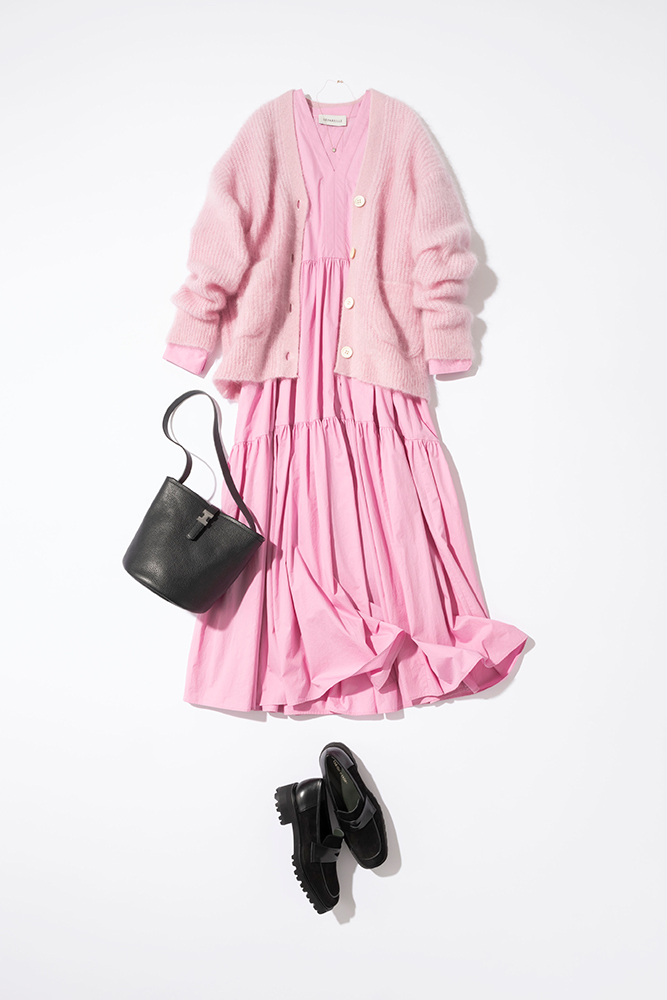 ピンクのロング丈のギャザーワンピースにピンクのニットカーデをはおり、黒のバッグと靴を合わせたコーデ写真