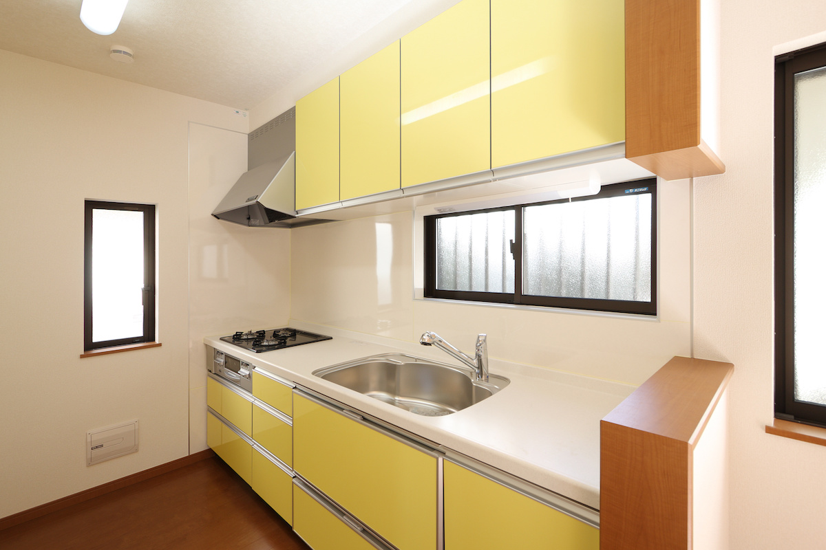白い天板と黄色の扉のI型キッチンの写真