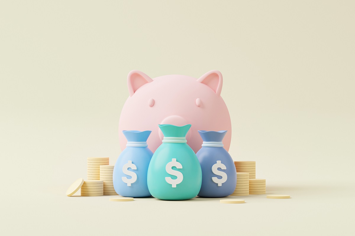 ピンクの豚の貯金箱、その前に置かれるドル袋とコイン