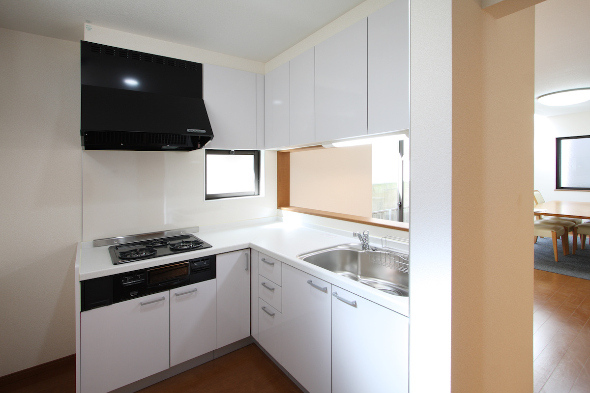 白くコンパクトな対面式L型キッチンの写真