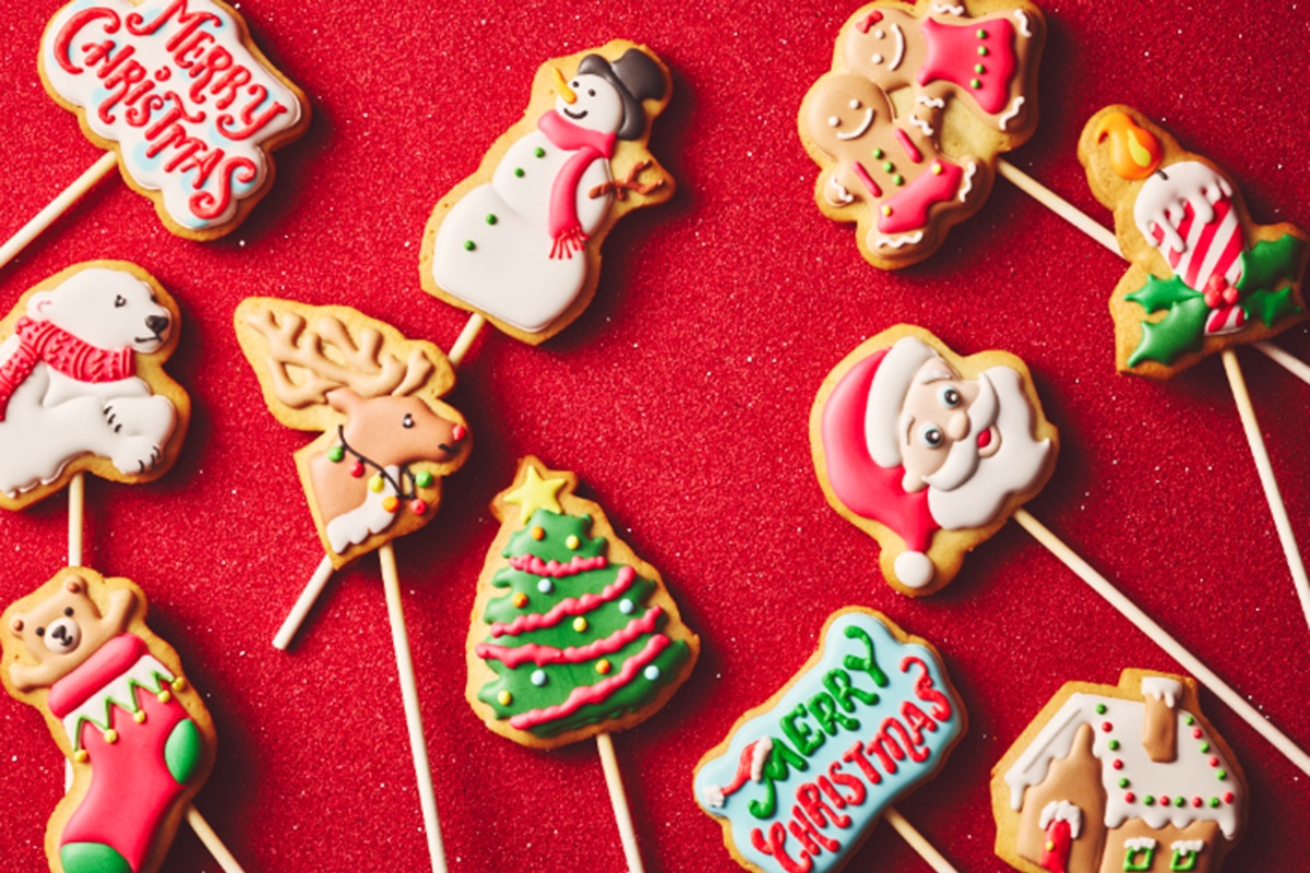 サンタクロース、スノーマンなどクリスマスのモチーフのアイシングクッキーがテーブルに並べられている様子