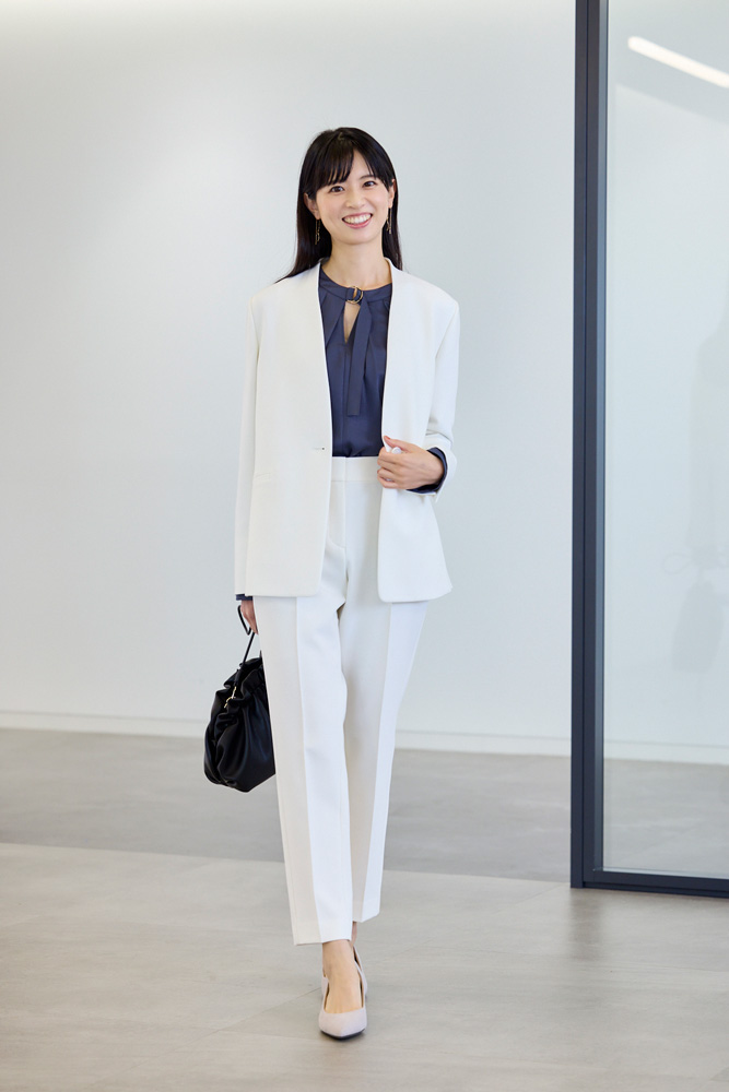 白のジャケットとパンツ、暗い色のブラウスを着用したモデルの画像