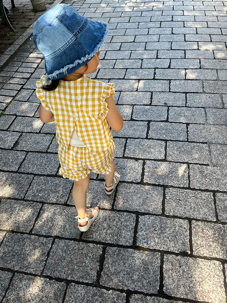 黄色チェック柄のセットアップ、デニムのハットを着用した女児の後ろ姿