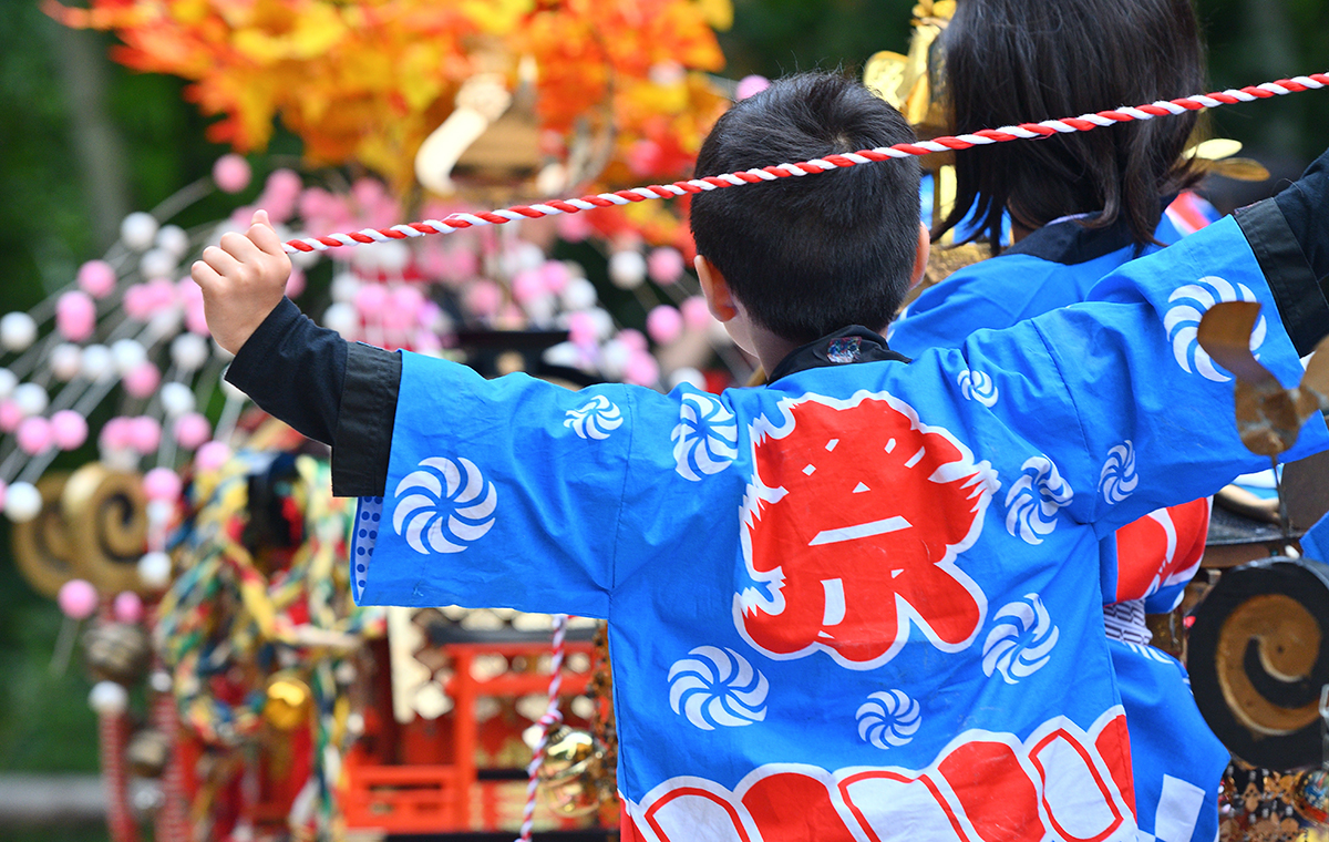 祭と書かれた法被を着た少年の後ろ姿