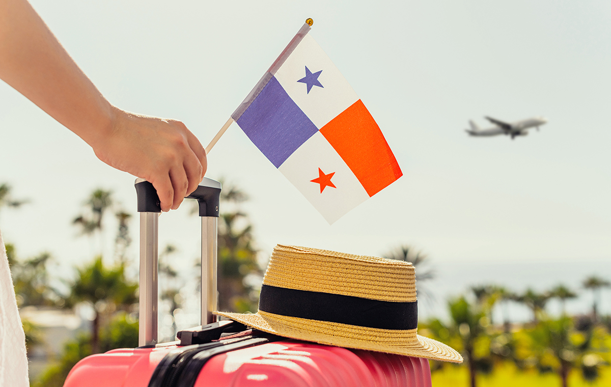 スーツケースとパナマの国旗を持った女性と空に飛行機が行く景色