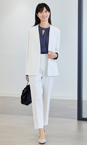 白のジャケットとパンツ、暗い色のブラウスを着用したモデルの画像
