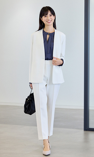 白のジャケットとパンツ、暗い色のブラウスを着用したモデル写真