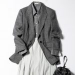 濃いめのグレーのジャケットにそれより少し薄いグレーのシャツ、さらに明るいグレーのスカートを合わせたコーデの上半身ショット