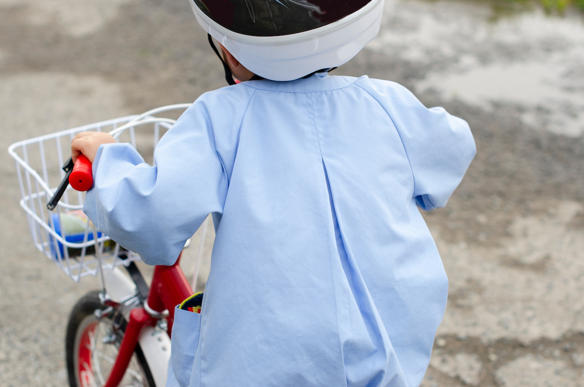 ヘルメットをかぶって三輪車に乗る子ども