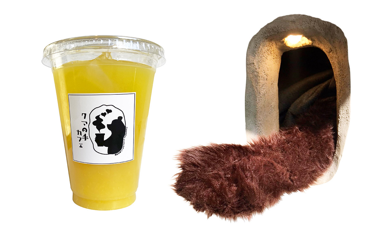 透明カップ入りのオレンジジュースと穴から覗く熊の着ぐるみの手の写真