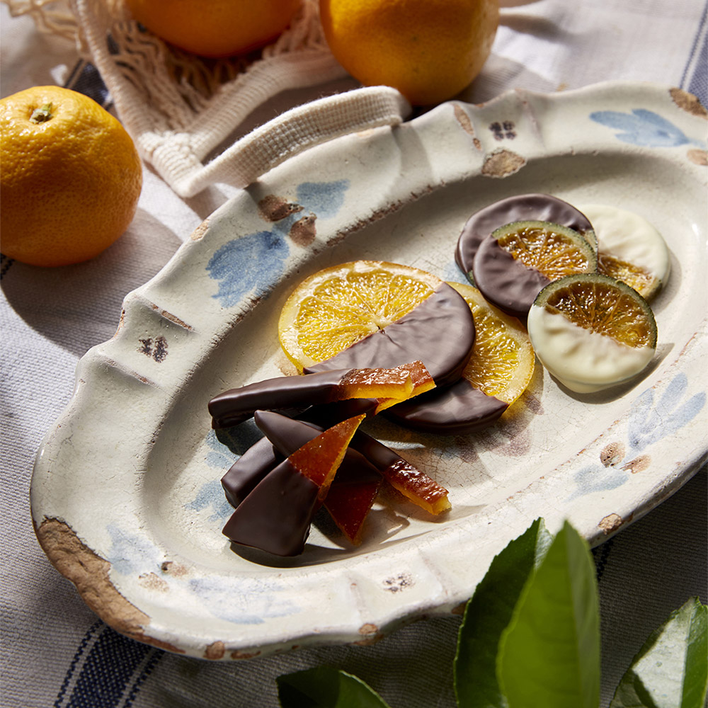 チョコレートがかかった輪切りやピール状の柑橘のお菓子がお皿に並べられた写真