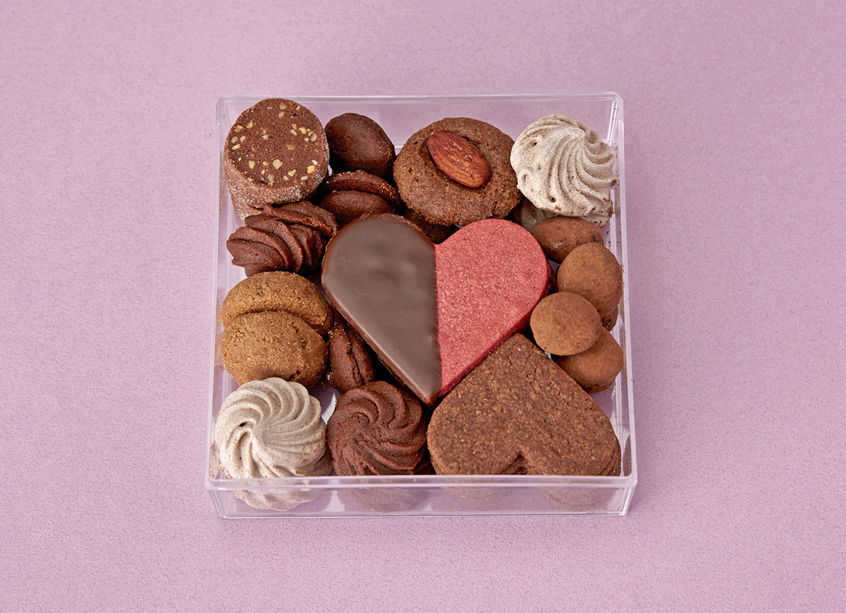 透明のボックスに詰められたハート型や丸など大小さまざまな形のクッキーの写真