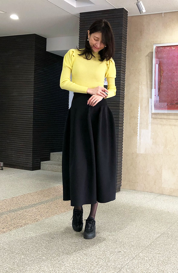黄色いトップスに黒のフレアスカートを着用した、ドマーニスト 飯島美穂さんの全身スナップ