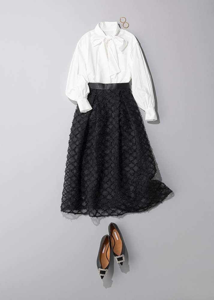 白のボウタイブラウスに刺繍デザインの黒のロングスカートを合わせたコーデ写真
