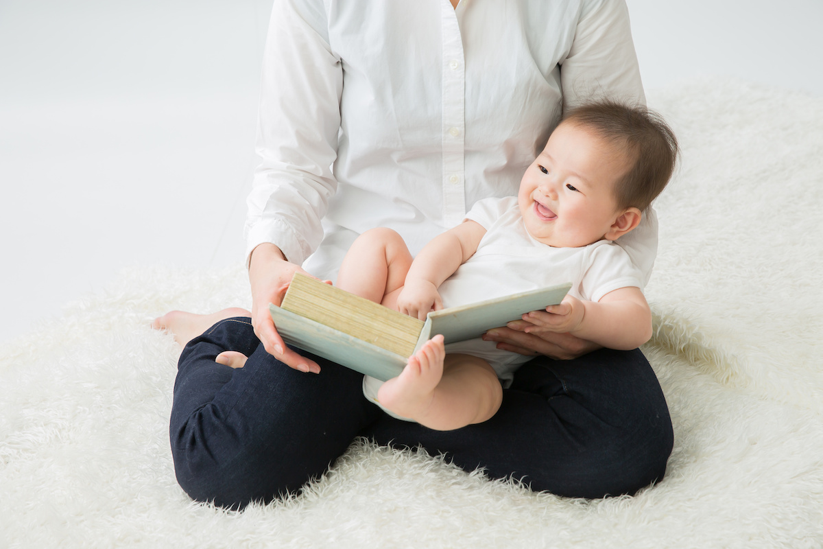 大人の膝の上で絵本を見る赤ちゃん
