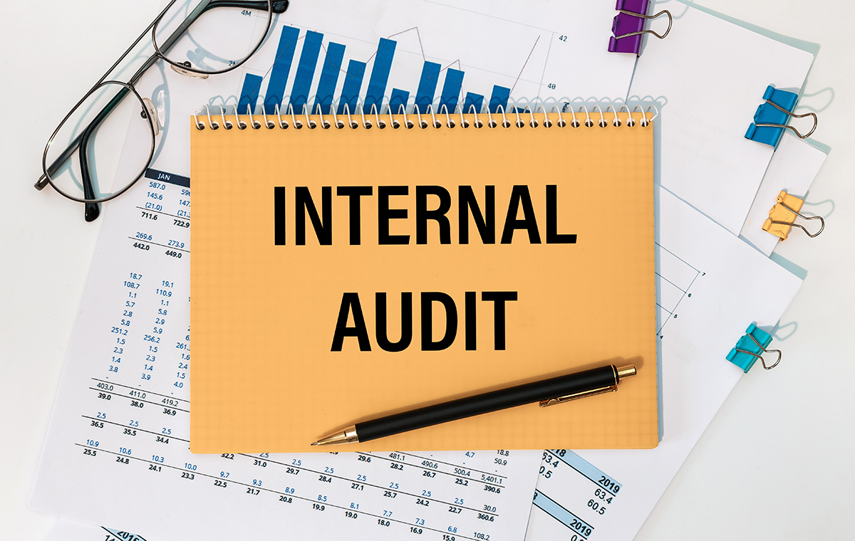 データや書類が重なっている内部監査のイメージ画像　ノートの表紙にInternal auditという文字が書かれている