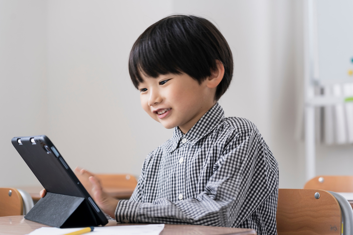 教室でタブレットPCを見る日本人小学生の男の子
