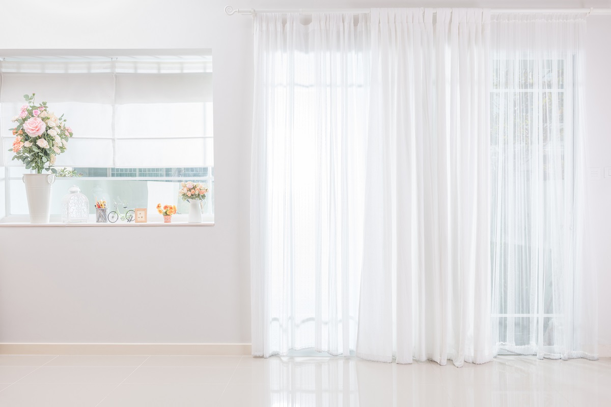 窓際の白いレースカーテン、花瓶が並べられた小窓のある部屋の写真