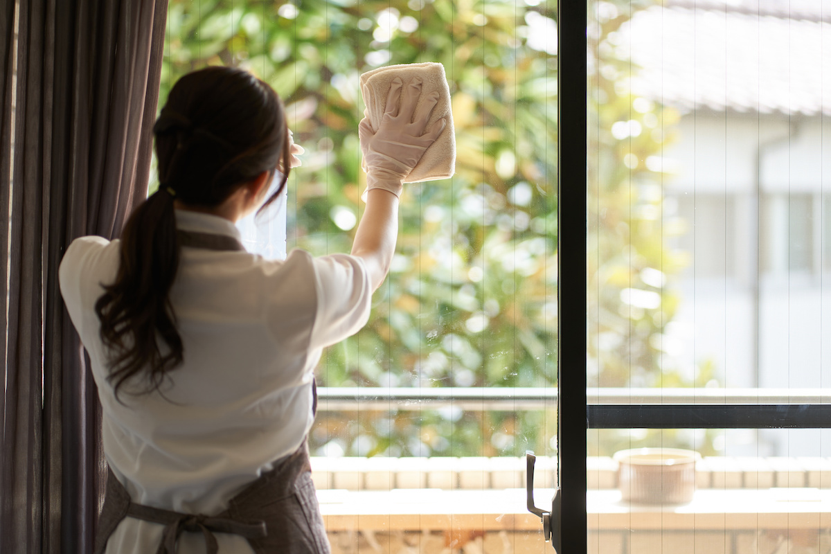 リビングの窓の拭き掃除をするアジア人女性