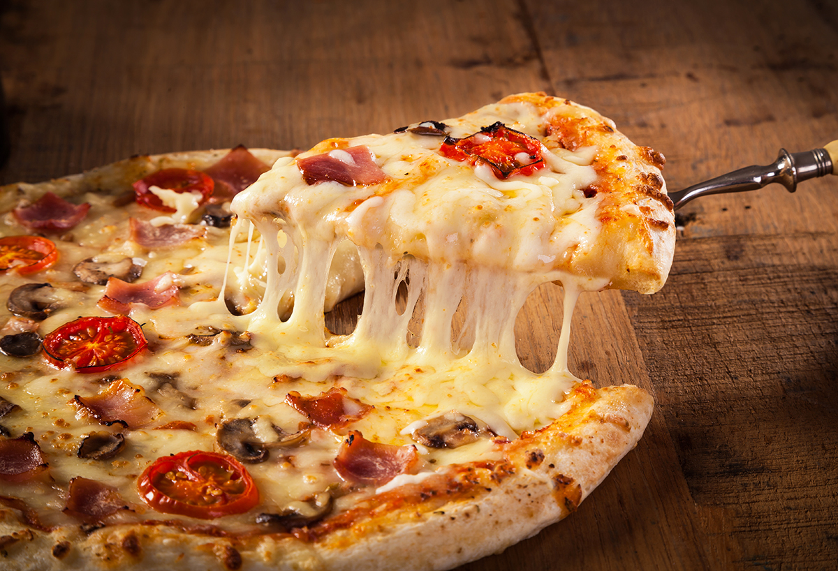 ピザの一切れを持ち上げ、チーズが伸びている様子の写真