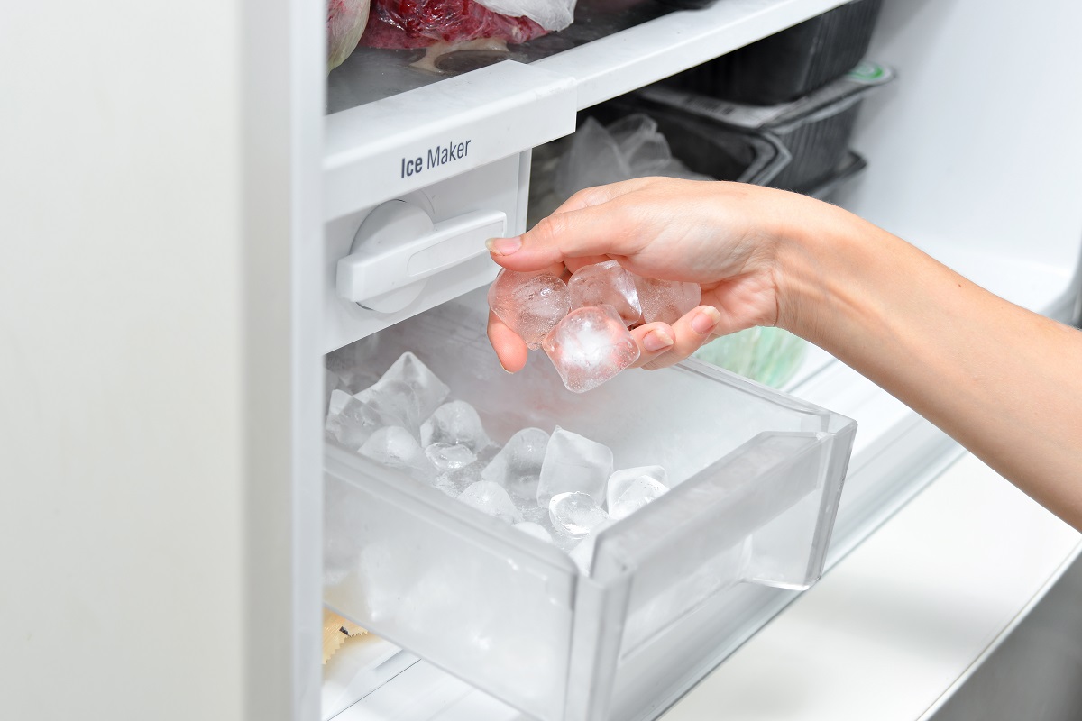 冷蔵庫の製氷器から氷を取り出している人の手元