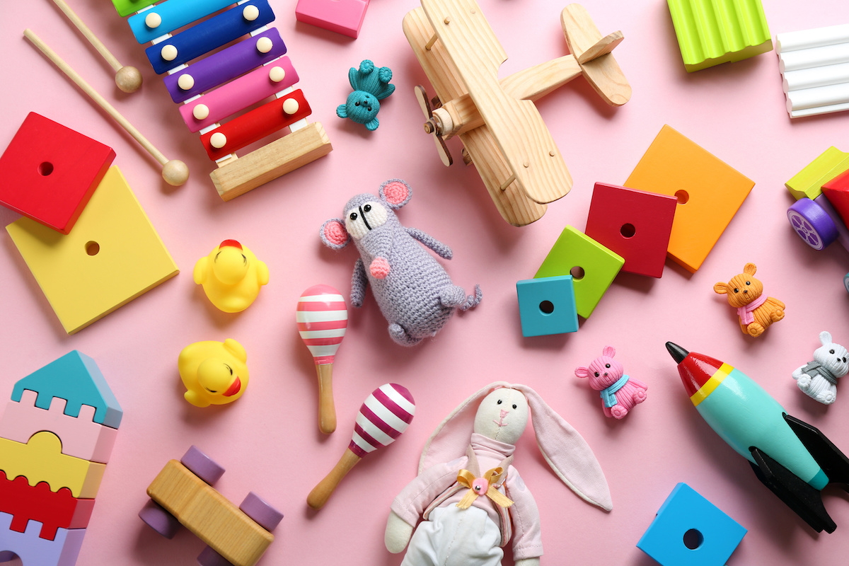 ピンクの背景に木製のおもちゃやぬいぐるみが並んでいる写真