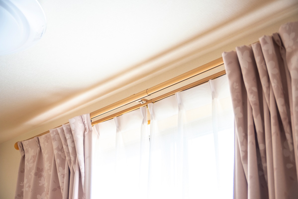 窓際のカーテンレールの写真　レースカーテンとピンクベージュのカーテンが取り付けられている
