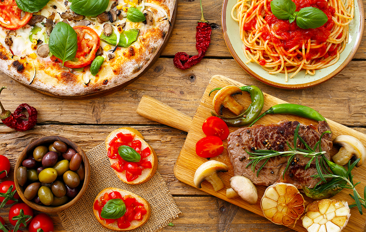ピザ、パスタ、グリルなどのイタリアンメニューが並ぶテーブルの写真