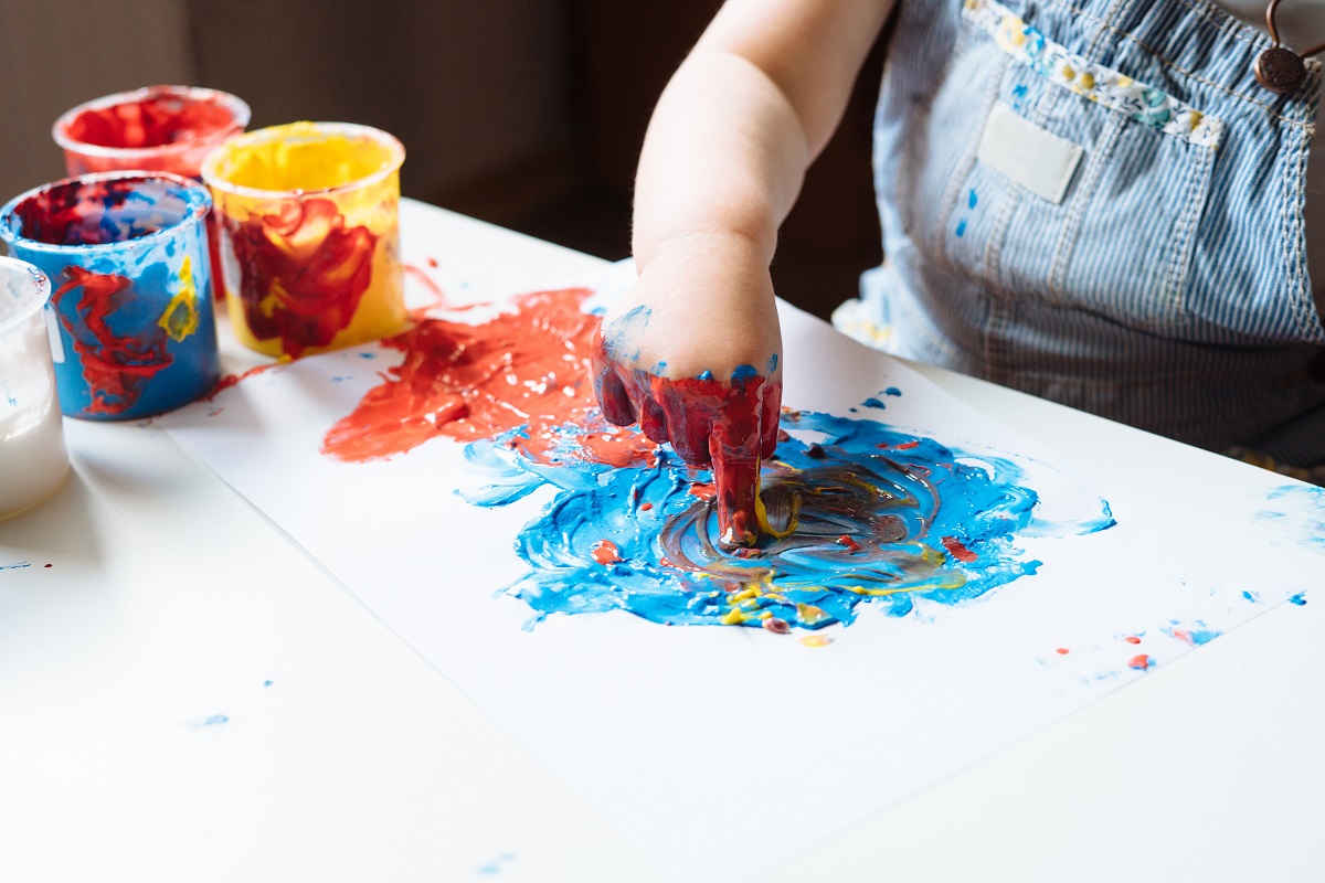子供が手を使って絵の具で絵を描いている手元の写真