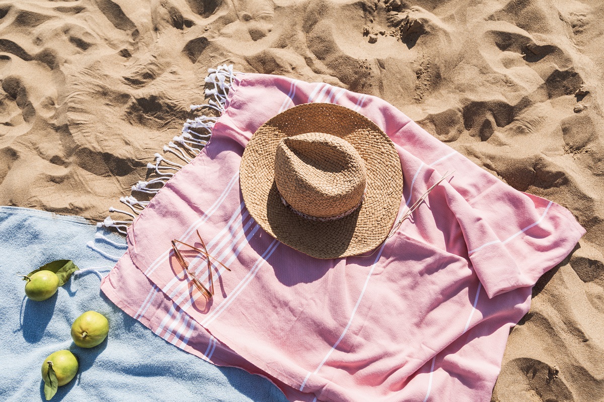砂浜の上に置かれたタオル、ストール、サングラスや帽子