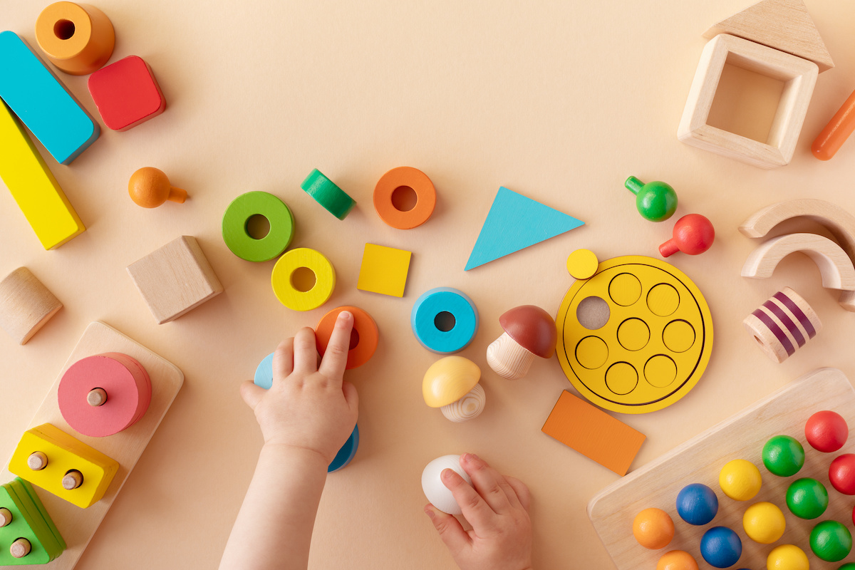 カラフルな木製おもちゃで遊ぶ子供の手元　イメージ写真
