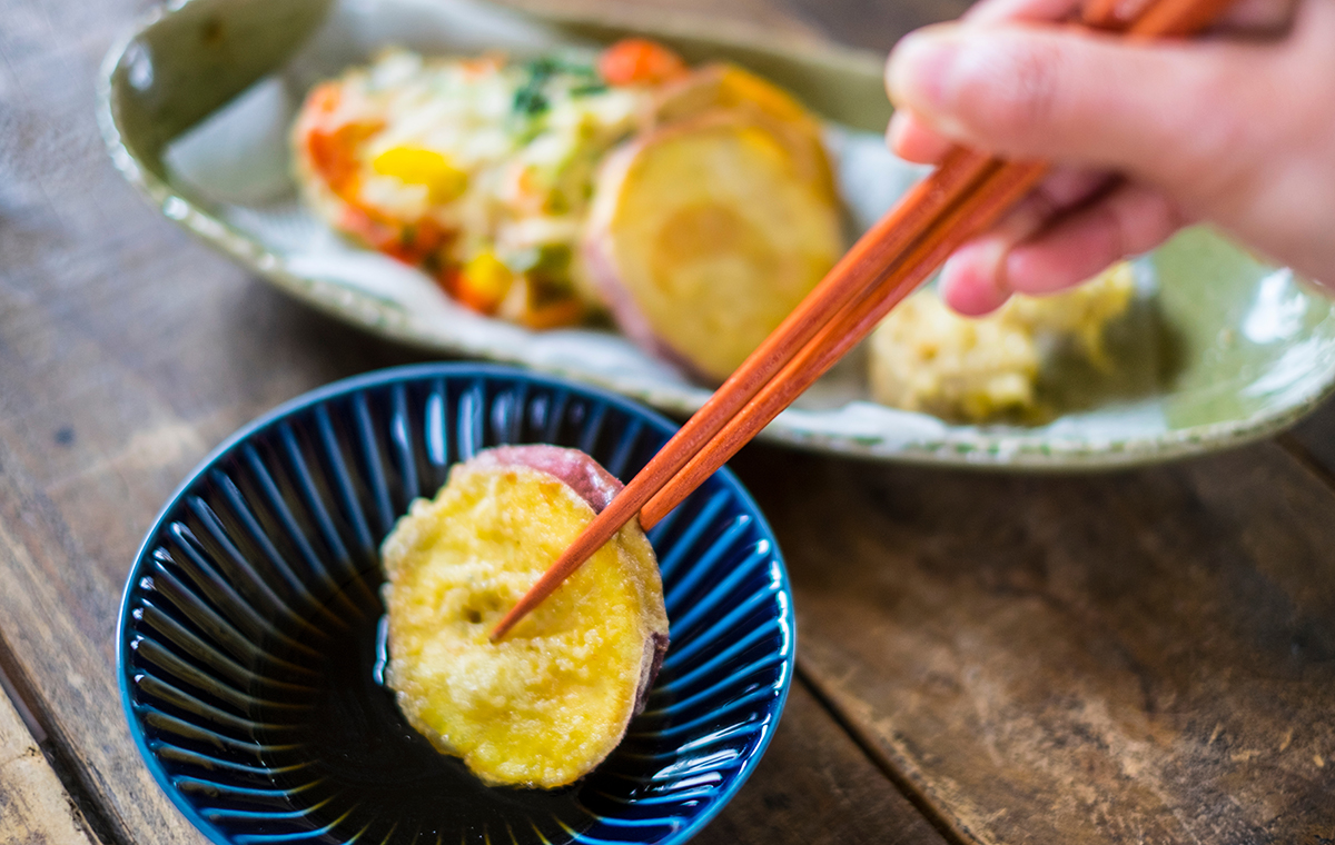さつま芋の天ぷらを箸で出汁につけている様子