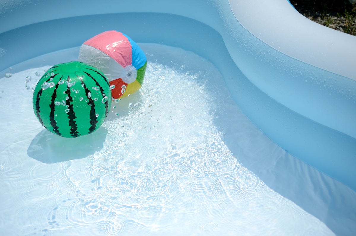 水色のプールに浮かんだスイカ柄とカラフルな色のビーチボールの写真